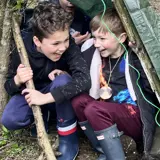 Two boys hiding in a den at the forest school